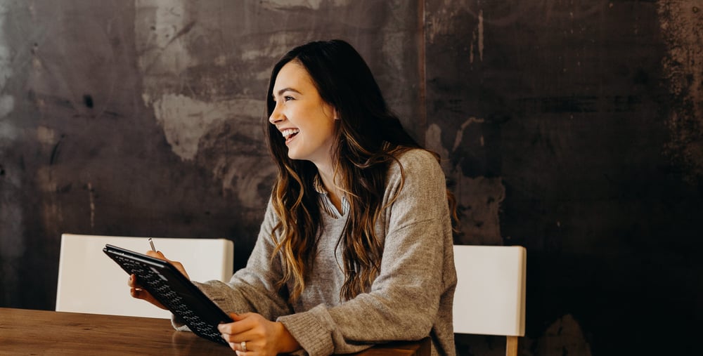 Glad tjej med anteckningsblock i handen