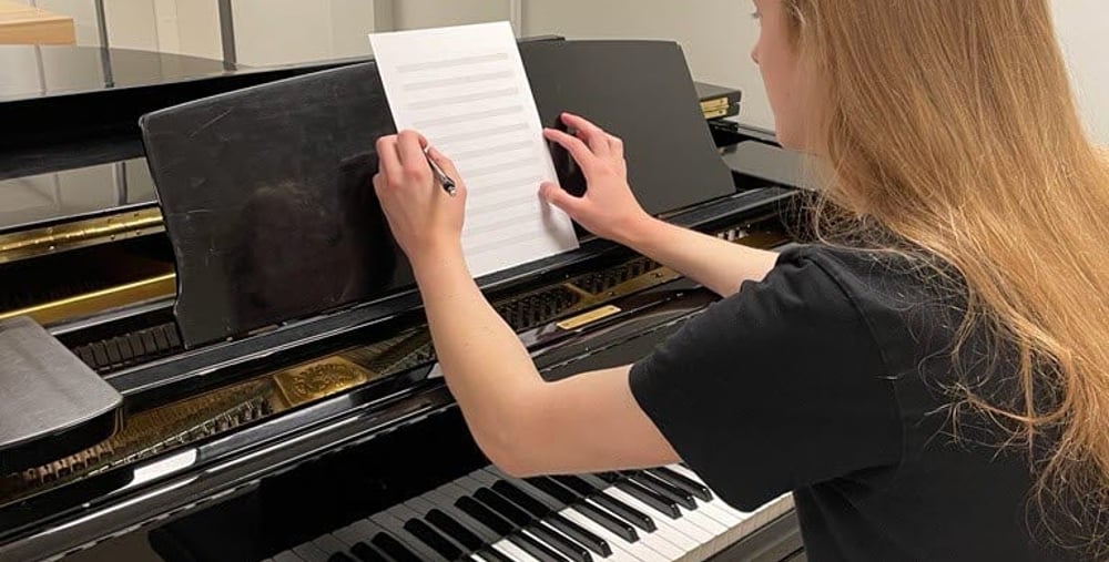 Person vid svart piano som komponerar musik