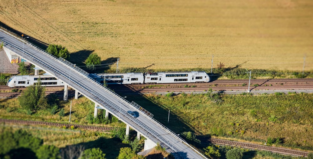 Ett tåg passerar under en landsväg.