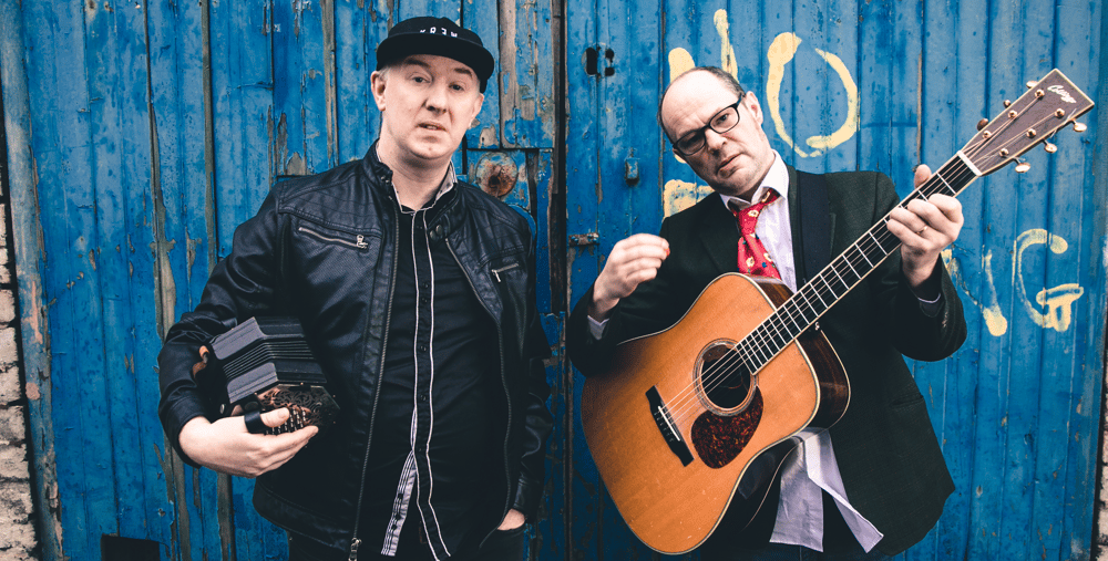 Två män som står bredvid varandra med gitarrer i händerna.