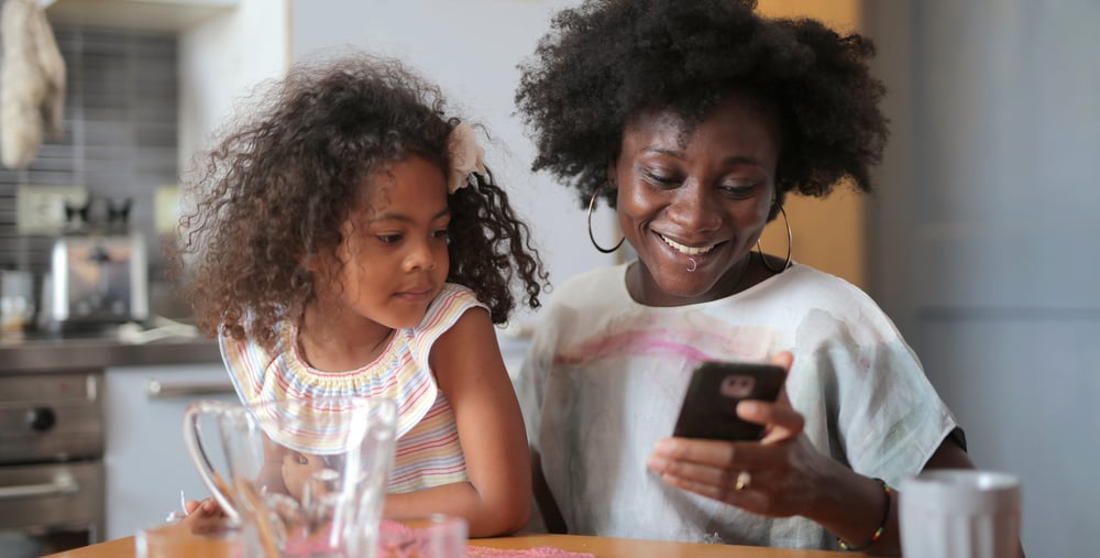 barn och vuxen tittar på mobiltelefon