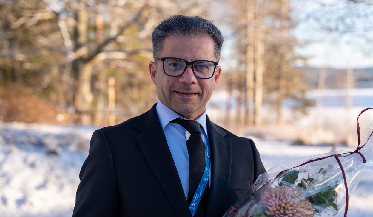 Årets medarbetare, Porträtt av en person i kostym som håller en bukett blommor utomhus i vintermiljö