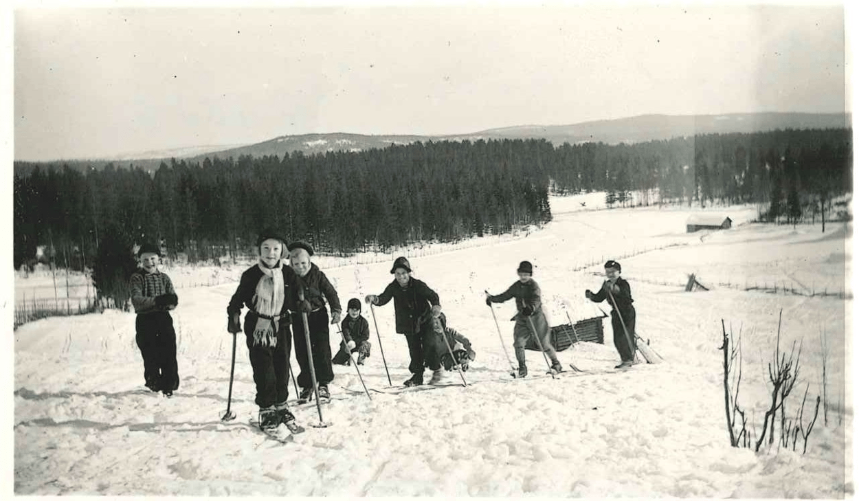 En grupp barn som åker skidor uppför en snötäckt sluttning.