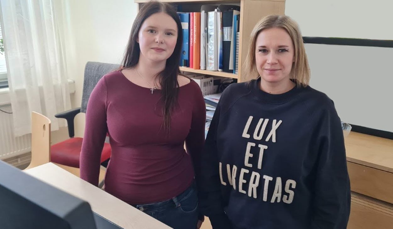 Studie- och yrkesvägledare Julia Wennbergen och hennes elev Tuva Kjellén Strandberg ståendes vid en dator inne på ett kontor