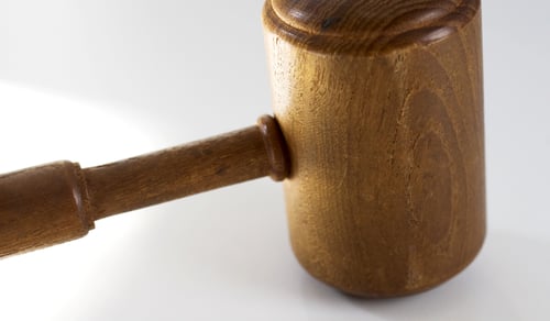En domarhammare i trä mot en vit bakgrund.