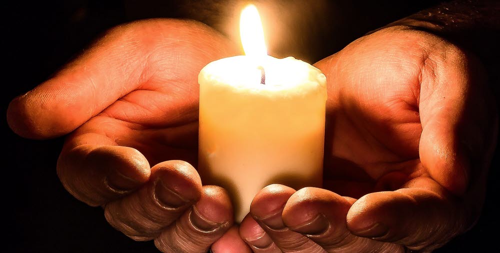 Händer med tänt ljus