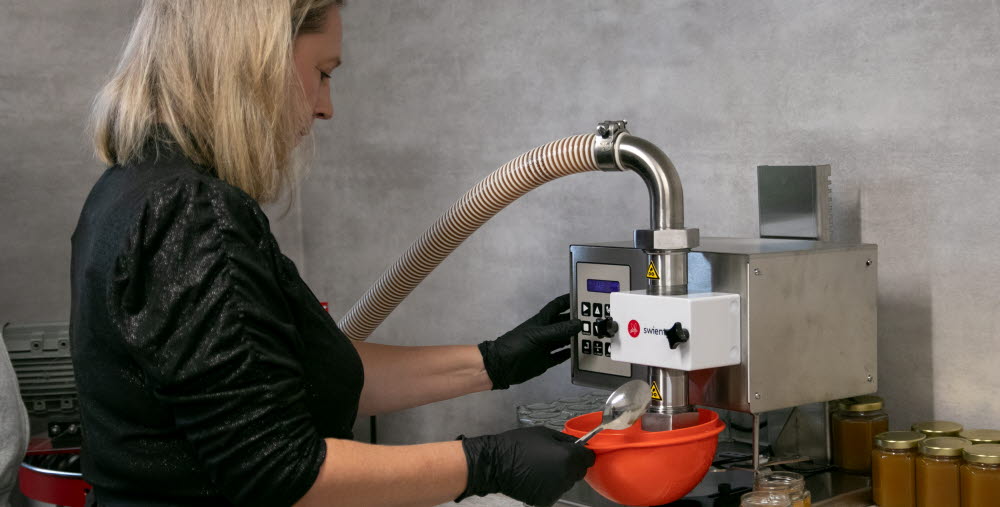 Kvinna tappar honung på burk.