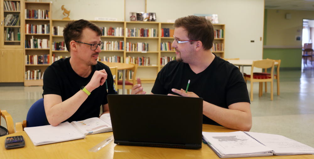 Två kursdeltagare sitter och studerar